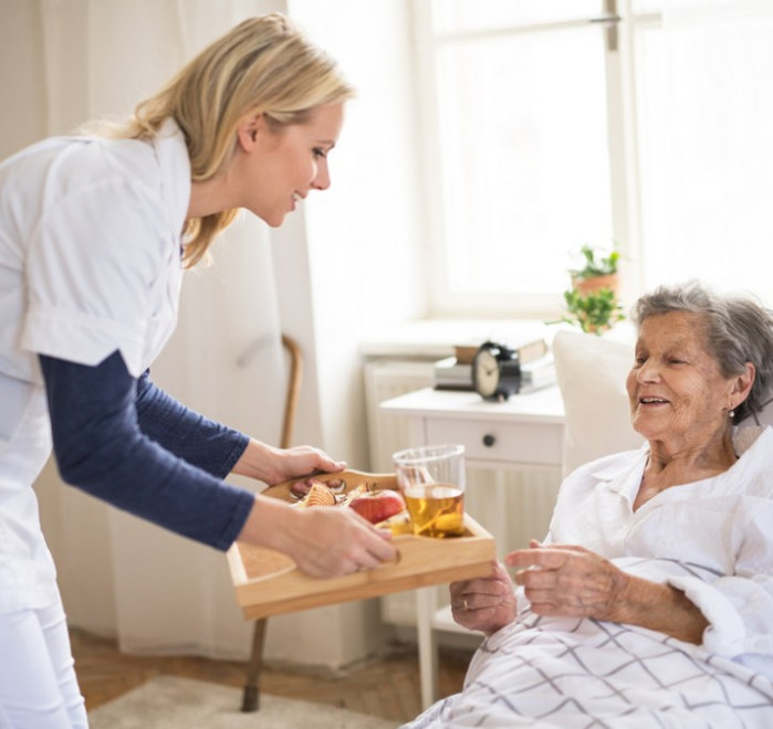 caregiver offering senior woman a meal